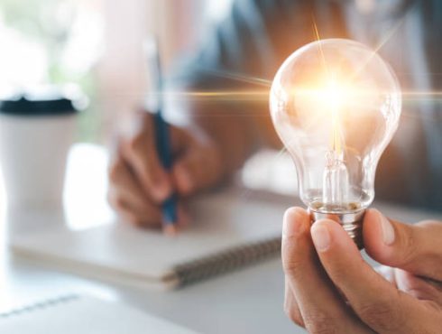 Innovation through ideas and inspiration ideas. Human hand holding light bulb to illuminate, idea of creativity and inspiration concept of sustainable business development.